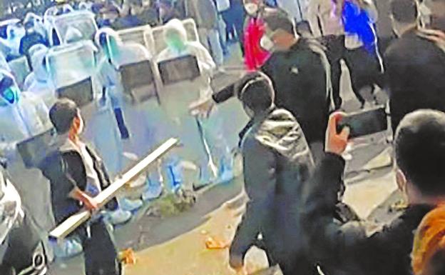 Trabajadores de la fábrica de iPhone en Zhengzhou, en el centro de China, se enfrentan a la Policía antidisturbios y a personas que vestían trajes contra materiales peligrosos.